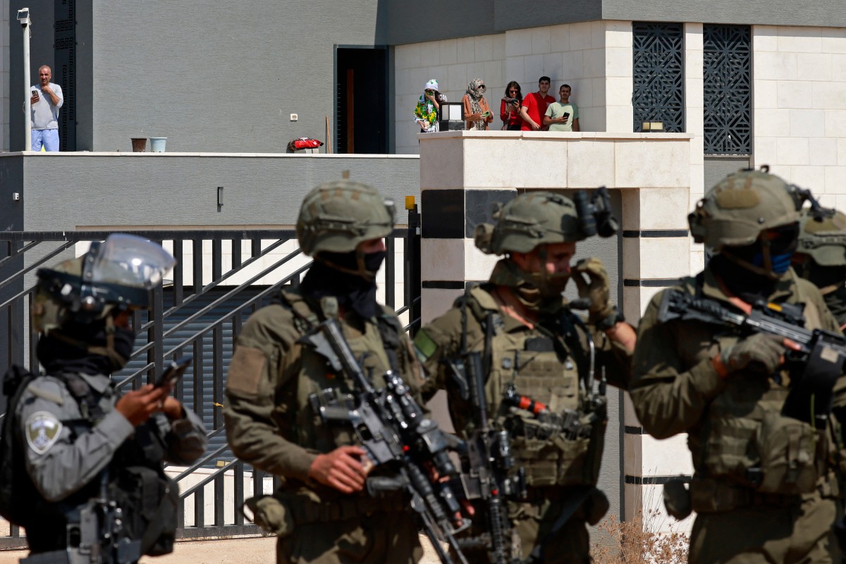 Israeli soldiers stand in front of the entrance of a besieged Palestinian house by Israeli settlers in the village of Qusra, south of Nablus, in the occupied West Bank. (File/AFP)