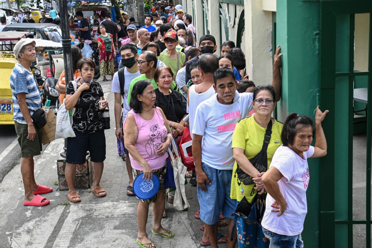 People wait in a queue outside a government-sponsored rolling store selling cheap rice near a public market in Manila on April 10, 2026. (AFP)