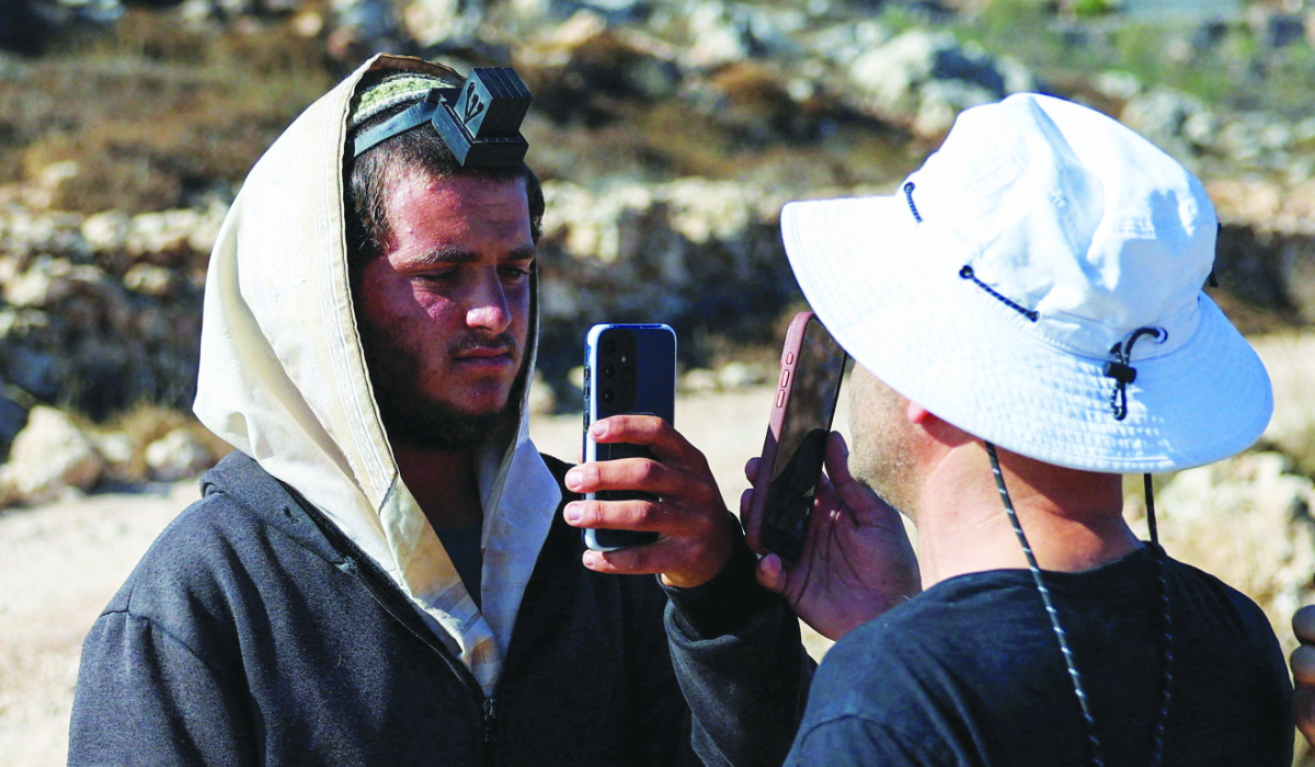 Palestinian-American Loui Ridi (R), whose house was encircled by militant settlers for over a week, films an Israeli settler (L) who entered his property in Qusra, Israeli-occupied West Bank, August 18, 2026. (REUTERS)