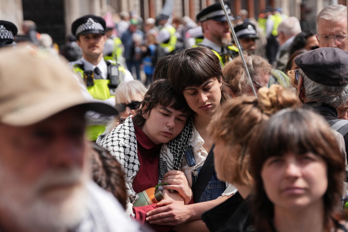People stand listening to the court proceedings outside the Royal Courts Of Justice in central London on June 15, 2026, as the High Court rules on a legal standoff between the government and activist group Palestine Action. (File/AFP)