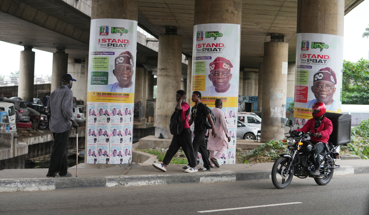 People walk past posters of Nigeria incumbent president, Bola Tinubu, of the All Progressives Congress Party on the streets in Lagos, Nigeria, Tuesday, Aug. 18, 2026. (AP)