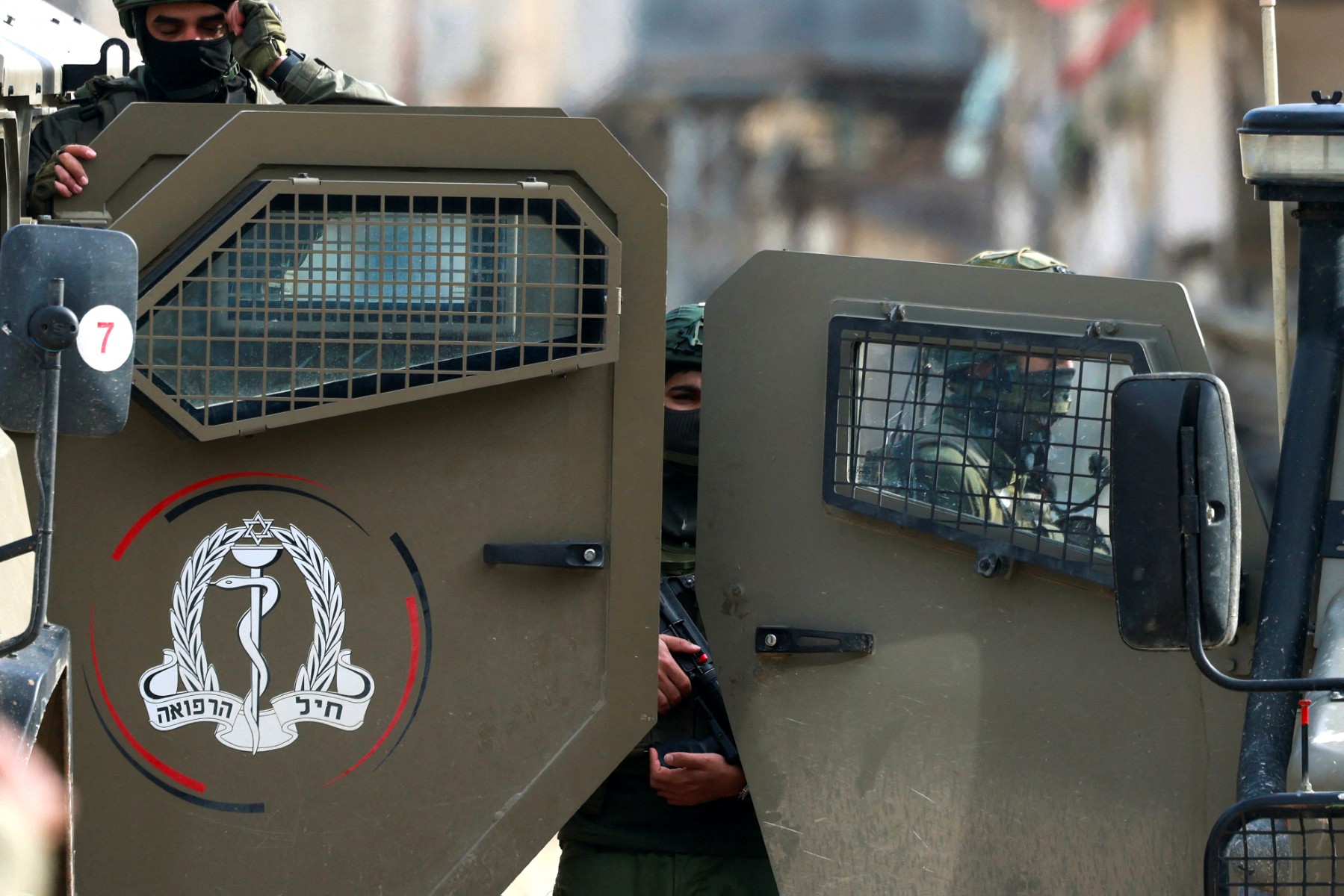 An Israeli soldier stands behind the doors of military vehicles parked at the entrance of the Nur Shams Palestinian refugee camp, in the Israeli-occupied northern West Bank, Dec. 15, 2025. (AFP)