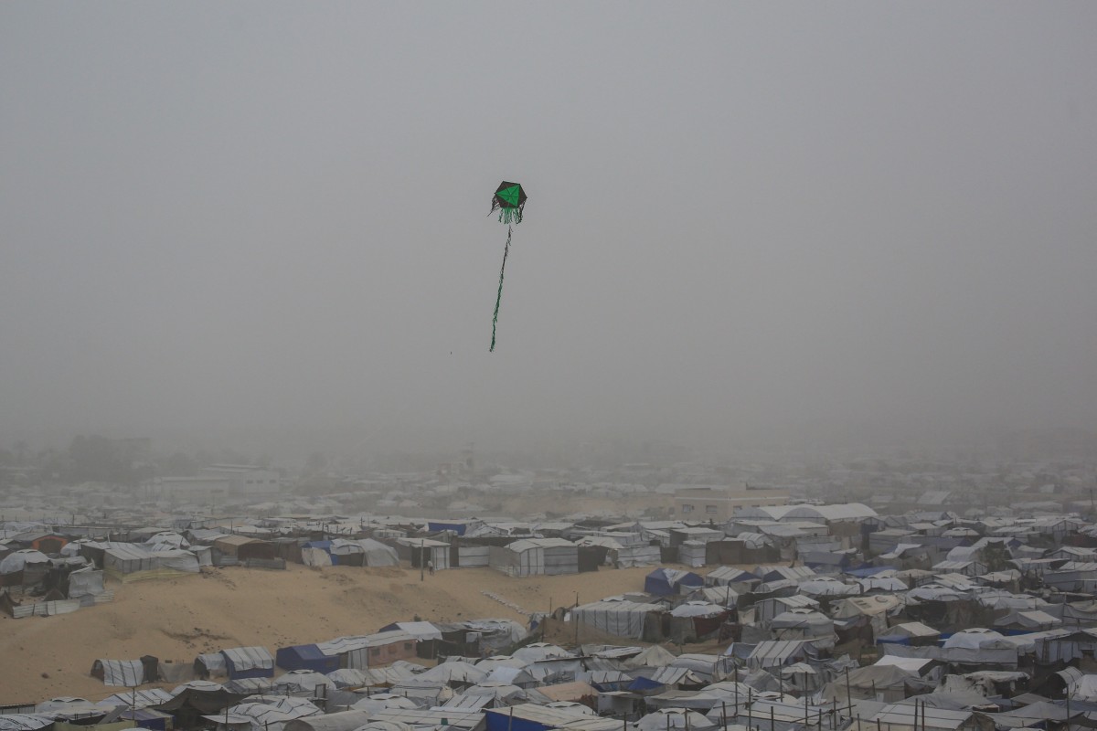 A kite flies over tents and makeshift shelters at a camp for displaced Palestinians during hazy and dusty weather in Khan Yunis, in the southern Gaza Strip, Feb. 14, 2026. (AFP / File)