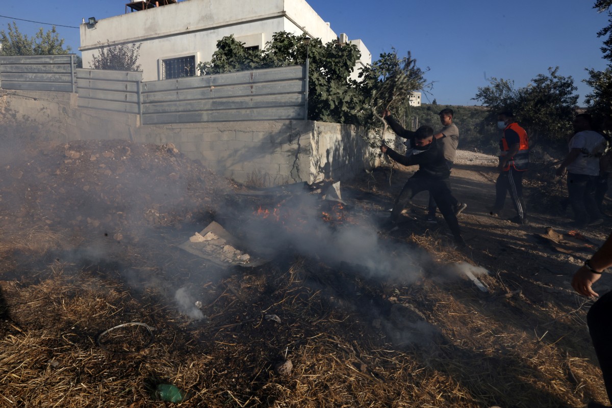 Palestinians extinguish a fire after vehicles and homes were torched in a reported settler attack in Sarra, near Nablus in the occupied West Bank, on July 24, 2026. (AFP)