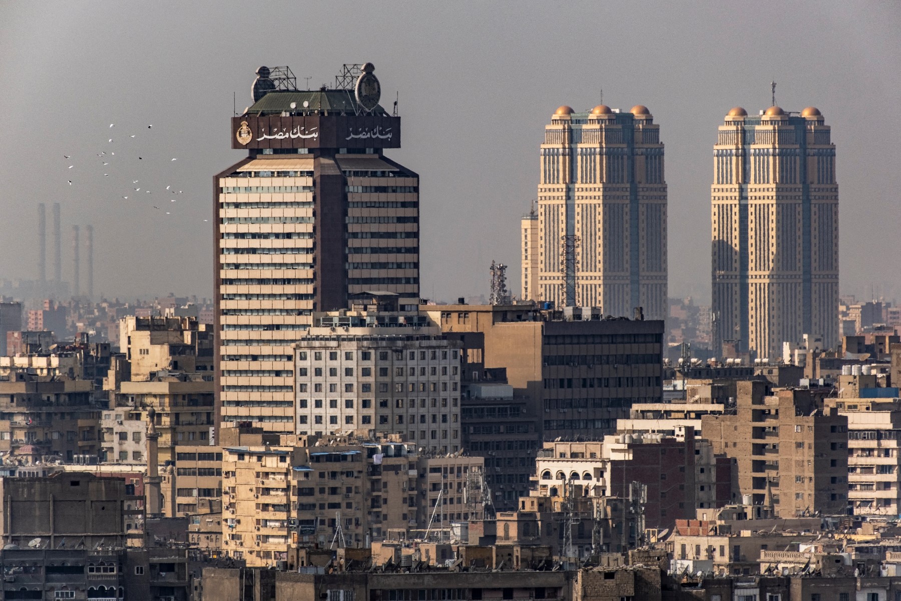 A flock of pigeons flies past the high-rise commercial building (L) serving as the modern headquarters of Banque Misr (Bank of Egypt), Egypt's first wholly nationally-owned bank (established in 1920), in Cairo on February 9, 2023. (AFP)