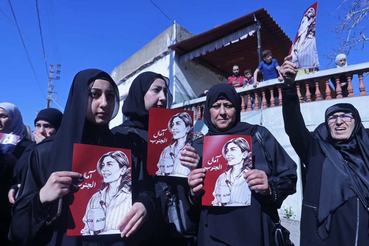 Mourners hold the portraits of Lebanese journalist Amal Khalil during her funeral procession in Bissariye town, south of Sidon on April 23, 2026. (AFP file photo)