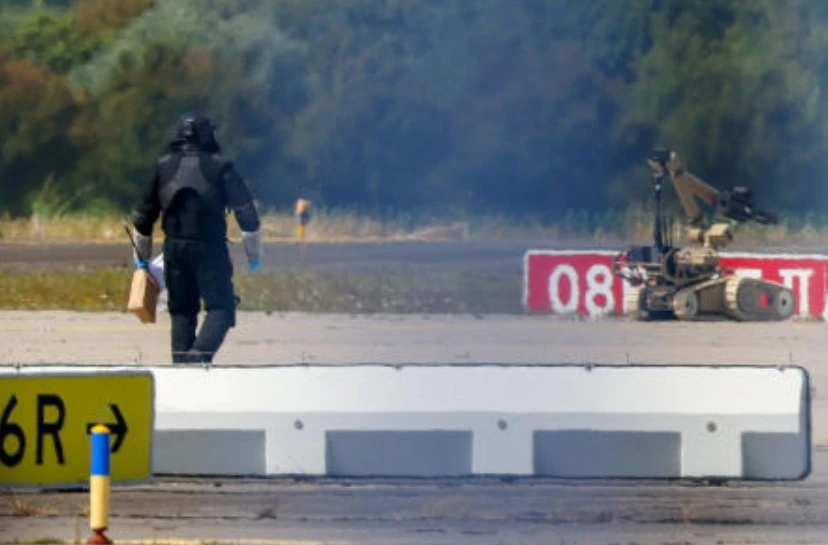 A police officer in protective clothing walks next to an explosive-disarming robot (EOD) at Leipzig/Halle Airport in Schkeuditz, Germany, Aug. 5, 2026. (Reuters)