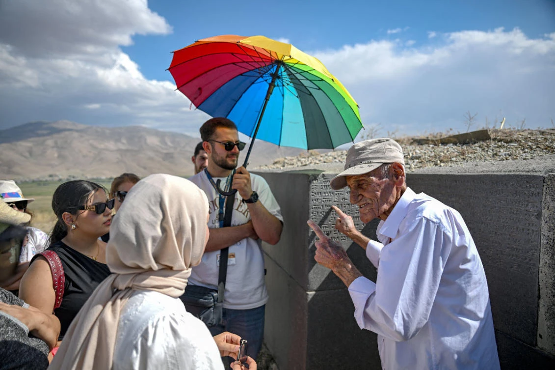 Mehmet Kusman, aged 86, who speaks Urartian language, reads a tablet engraved with Urartu language at the fortress of Cavustepe near Van, in eastern Turkey, on July 22, 2026. (Photo by Ozan Kose / AFP)