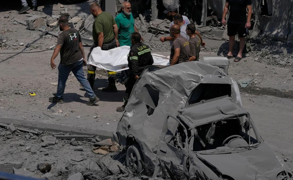 Rescue workers carry the body of a person, who was killed at a house that was hit by an Israeli airstrike, in Deir Al-Zahrani village, southern Lebanon, Saturday, Aug. 15, 2026. (AP Photo)