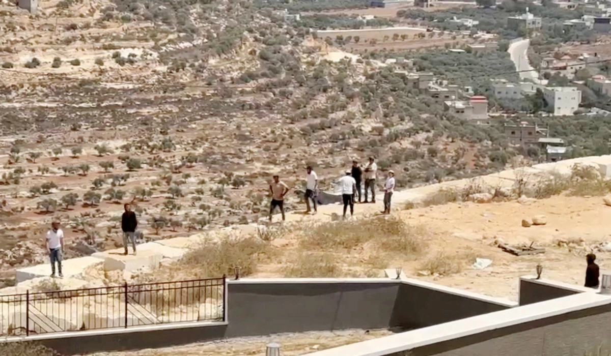 Israeli settlers gather outside a Palestinian home in Qusra, in the Israeli-occupied West Bank, August 15, 2026, in this screen grab obtained from a video. (REUTERS)