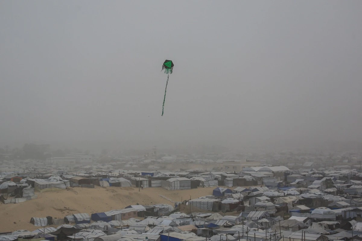 A kite flies over tents and makeshift shelters at a camp for displaced Palestinians during hazy and dusty weather in Khan Yunis, in the southern Gaza Strip, Feb. 14, 2026. (AFP / File)