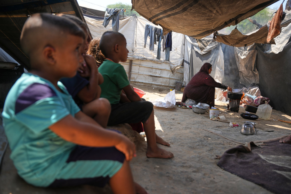 Young children await as their mother prepares a meal at the family's tent in Deir al-Balah, Gaza Strip. (AP)