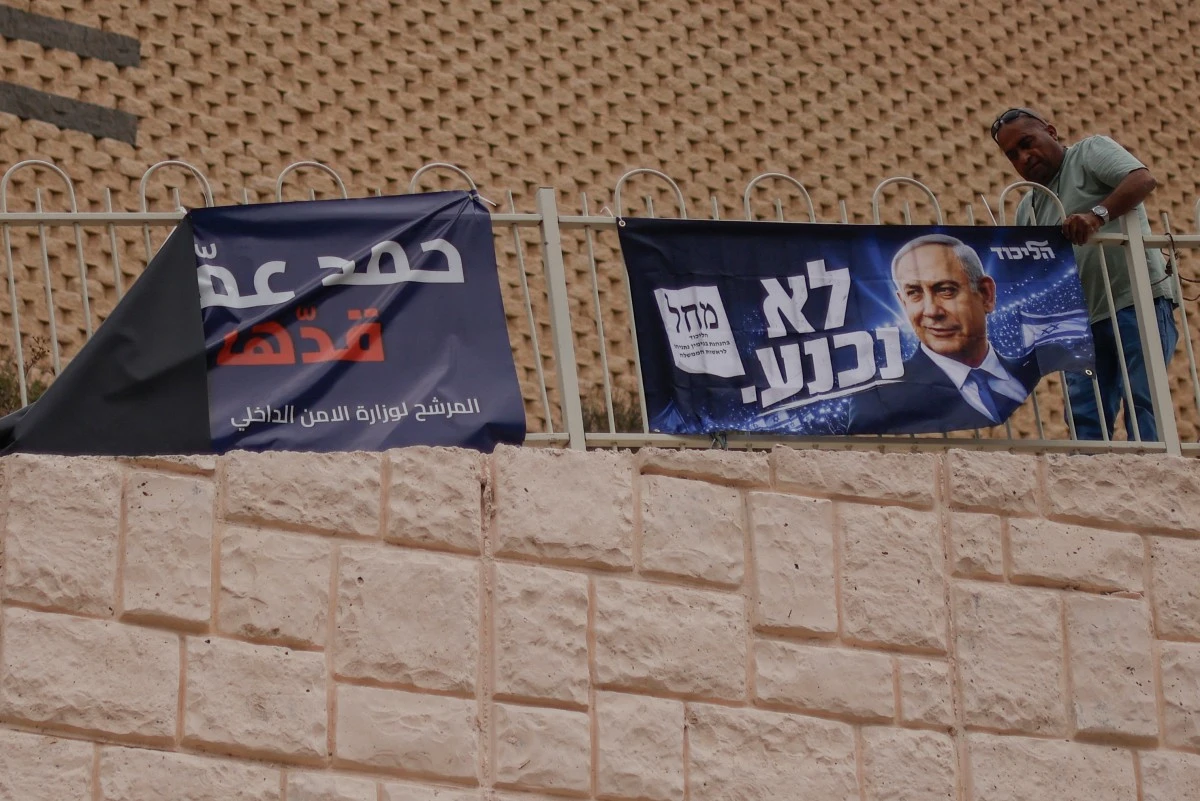 A man unfurls an election campaign poster for Israel's Prime Minister and head of the Likud party Benjamin Netanyahu, on a fence at the Druze village of Majdal Shams in the Israeli-annexed Golan Heights on October 17, 2026. (AFP)
