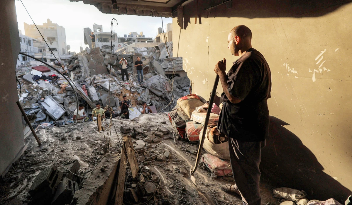 A man stands next to salvaged items as people search the rubble of a collapsed building following overnight Israeli airstrikes in Gaza City on October 9, 2026. (AFP)