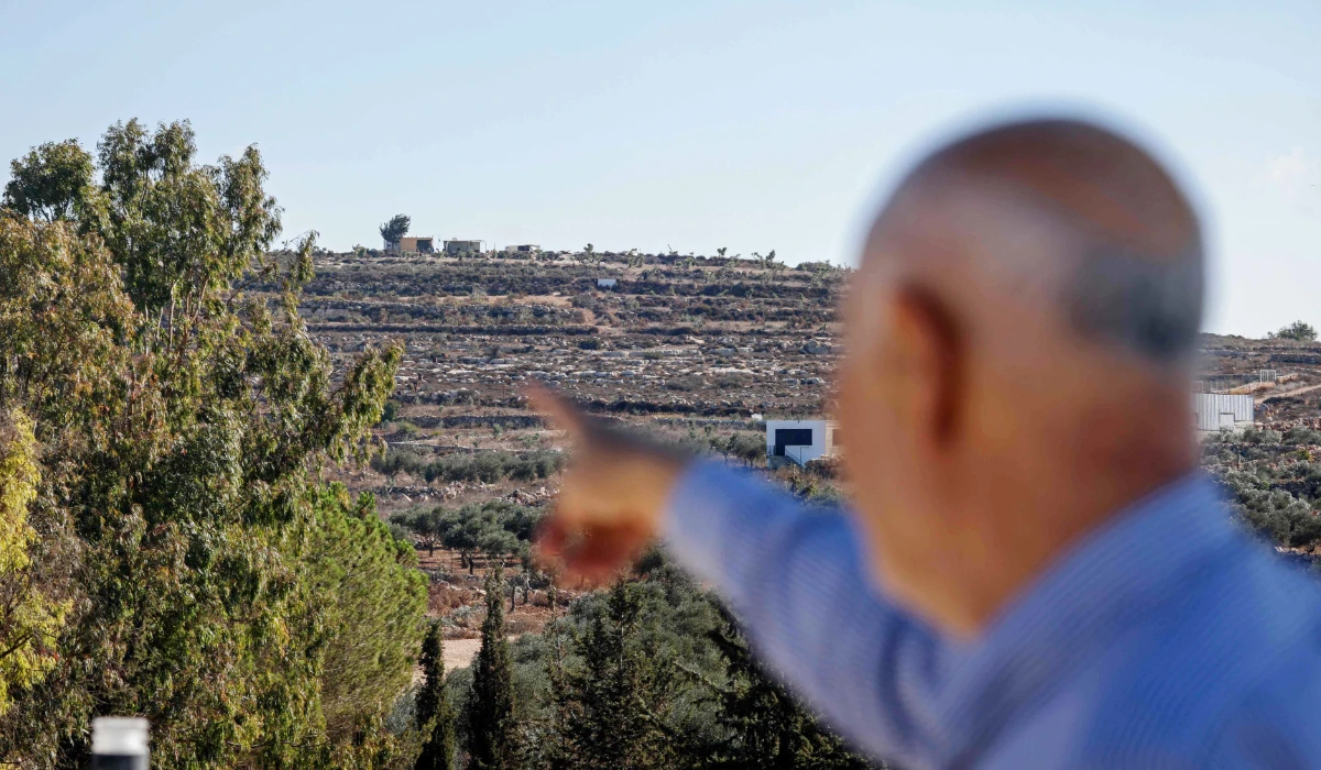 A Palestinian man points to a newly established Israeli settlers' outpost on a hill, north of Abu Falah village, northeast of Ramallah, in the Israeli-occupied West Bank on September 27, 2026. (AFP)