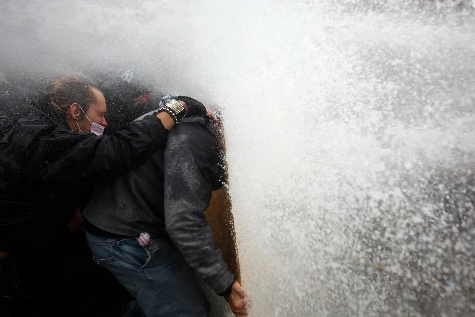 Protesters take cover behind a plywood board as French riot police use a water canon amid clashes during a demonstration in Paris on Saturday. (Reuters)