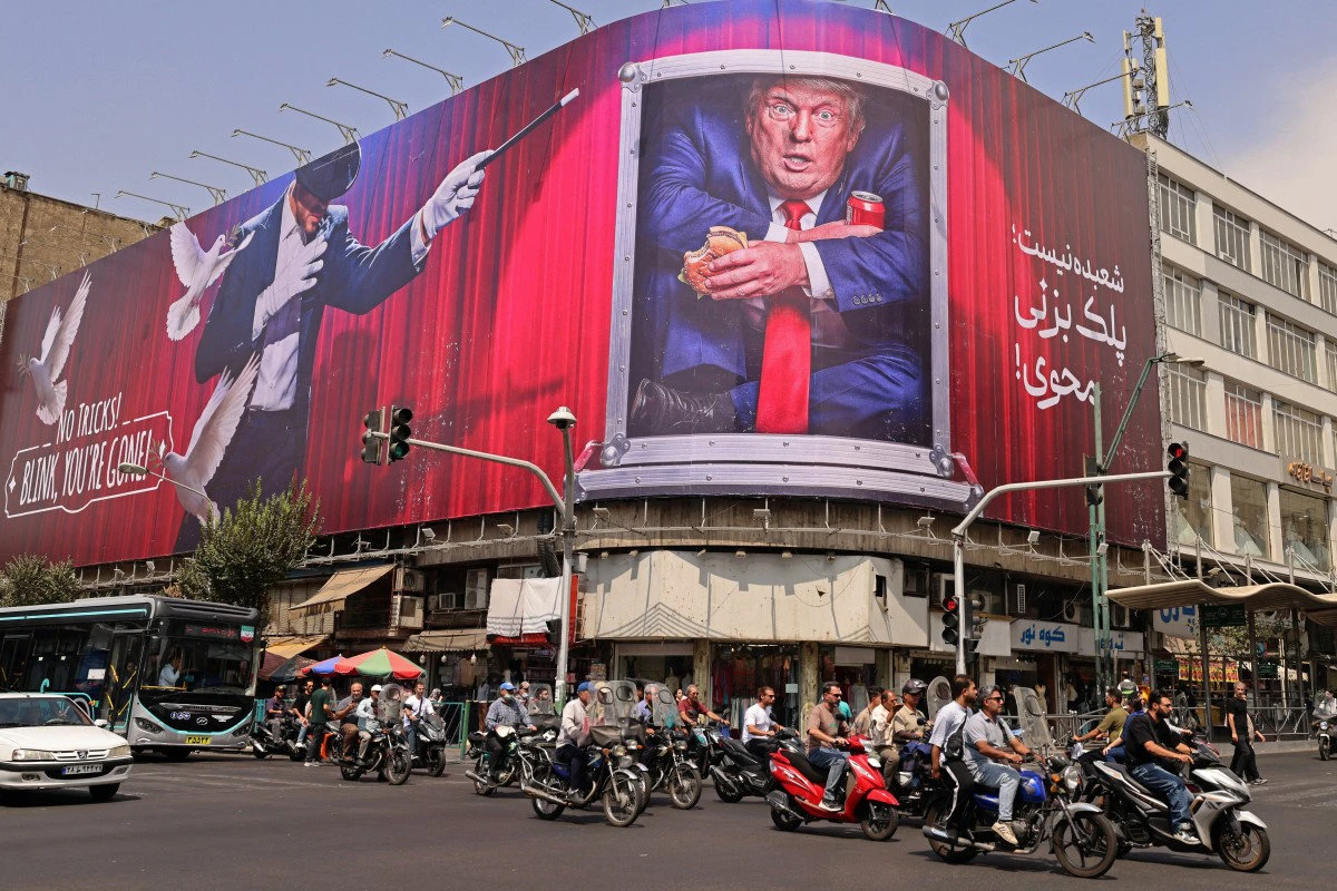 Motorists ride past a billboard depicting US President Donald Trump inside a catering container, installed on a building along a street in downtown of Tehran on August 31, 2026. (AFP)