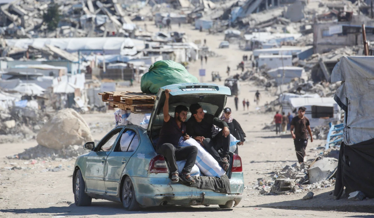 Palestinians drive a car loaded with belongings along a street lined with destroyed buildings and makeshift shelters at the Jabalia refugee camp in the northern Gaza Strip on October 5, 2026. (AFP)
