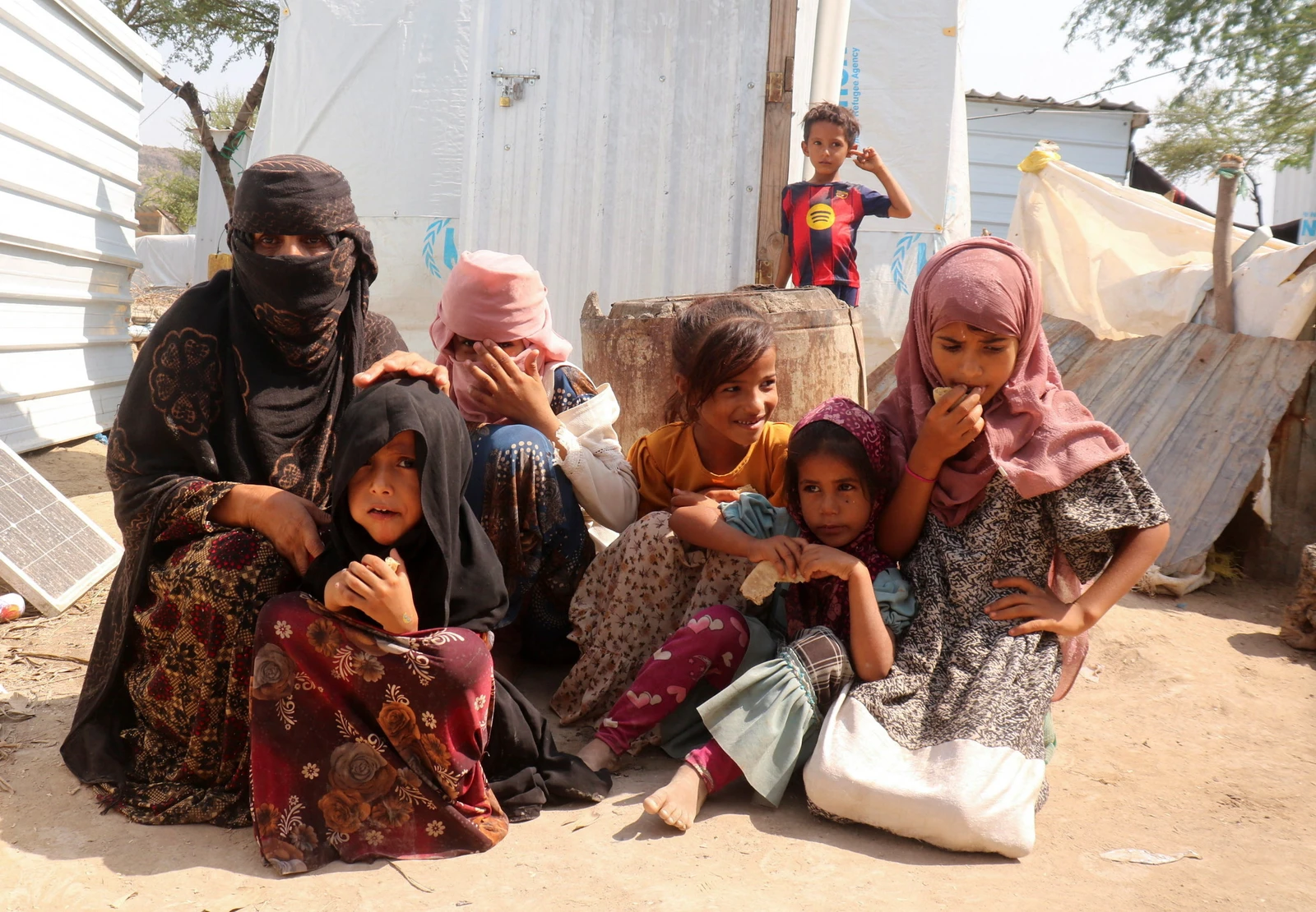 Rawya Hassan, a mother of seven, sits with her children outside their hut at the Al-Bireen camp for displaced people who fled fighting between the Houthis and forces of Yemen's internationally recognized government in Taiz province, Yemen, September 17, 2026. REUTERS/Stringer