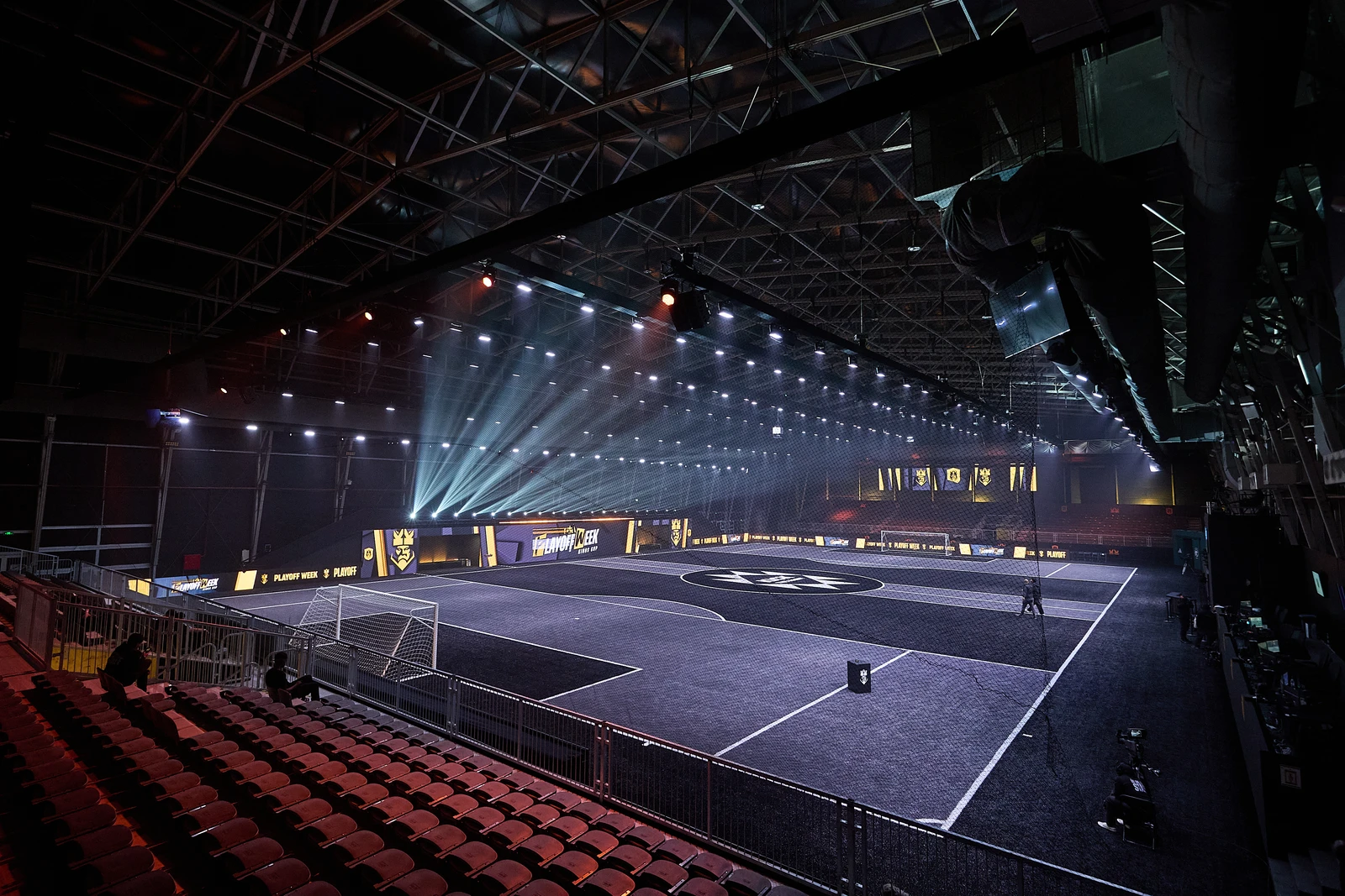 An empty indoor sports arena with dramatic lighting and a futuristic playing field.