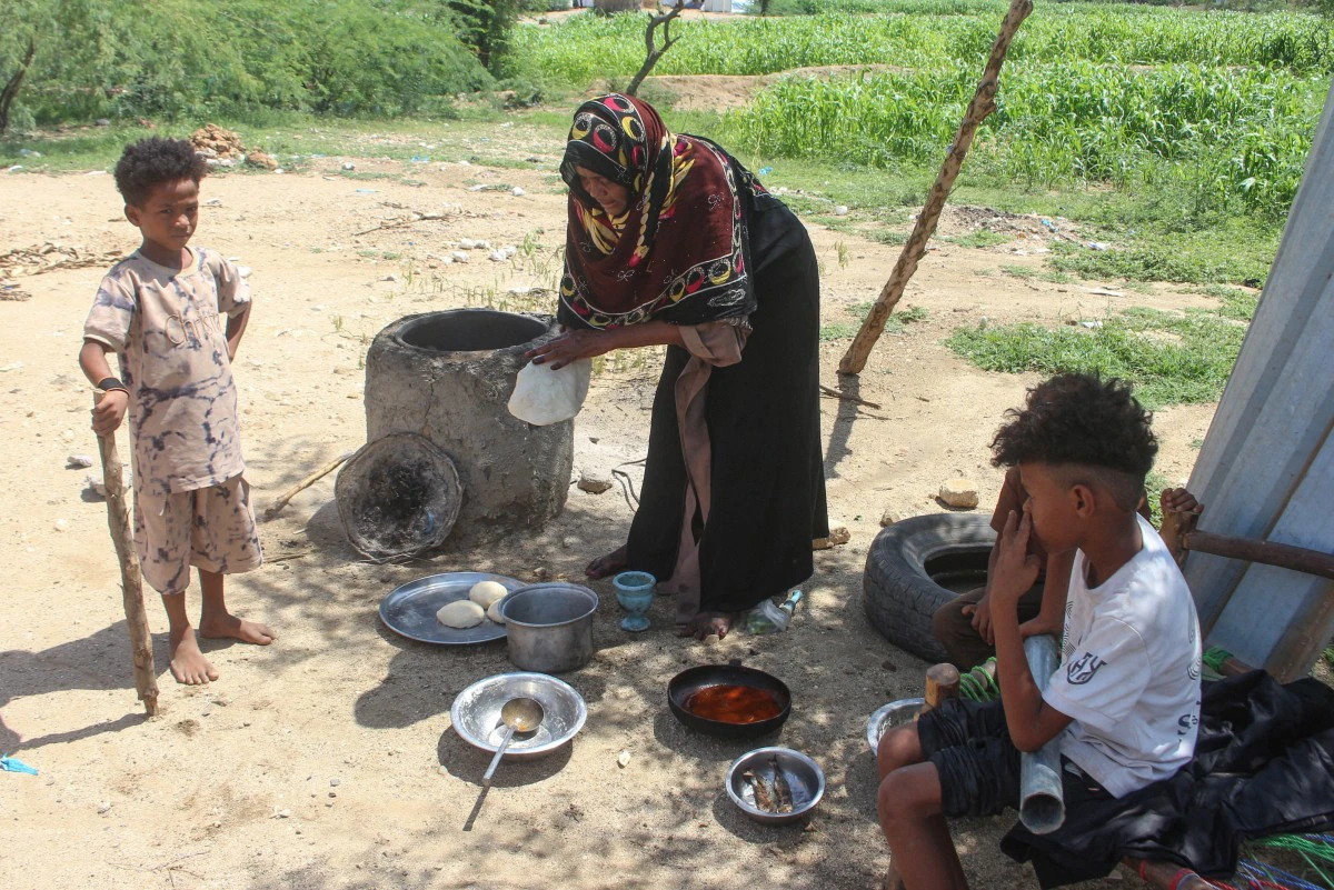A Yemeni woman cooks a meal for her children at a makeshift camp for people fleeing renewed clashes between Yemen’s government forces and the Houthi militia in the northern Hajjah governorate on October 7, 2026. (AFP)