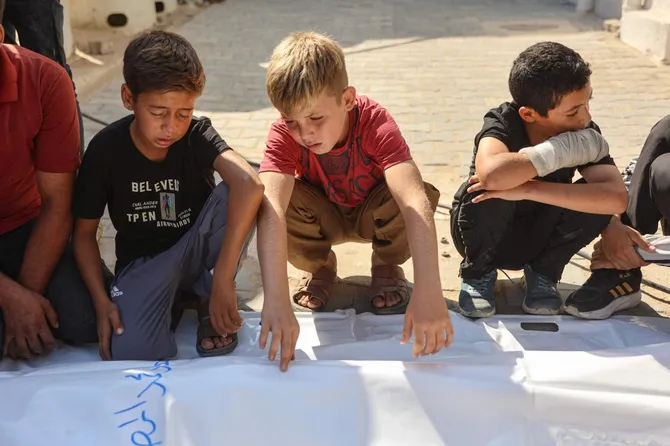 Boys mourn beside the bodies of Palestinian victims killed in an Israeli army strike on Gaza City's port the previous day, during their funeral in Gaza City on August 19, 2026. (AFP)