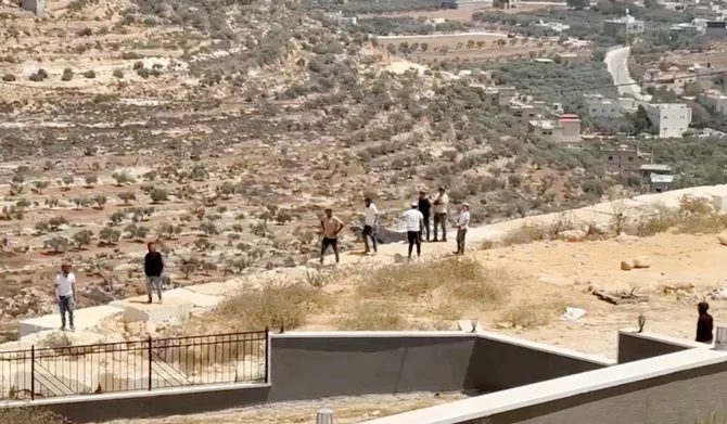 Israeli settlers gather outside a Palestinian home in Qusra, in the Israeli-occupied West Bank, August 15, 2026, in this screen grab obtained from a video. (REUTERS)