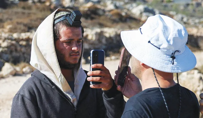 Palestinian-American Loui Ridi (R), whose house was encircled by militant settlers for over a week, films an Israeli settler (L) who entered his property in Qusra, Israeli-occupied West Bank, August 18, 2026. (REUTERS)