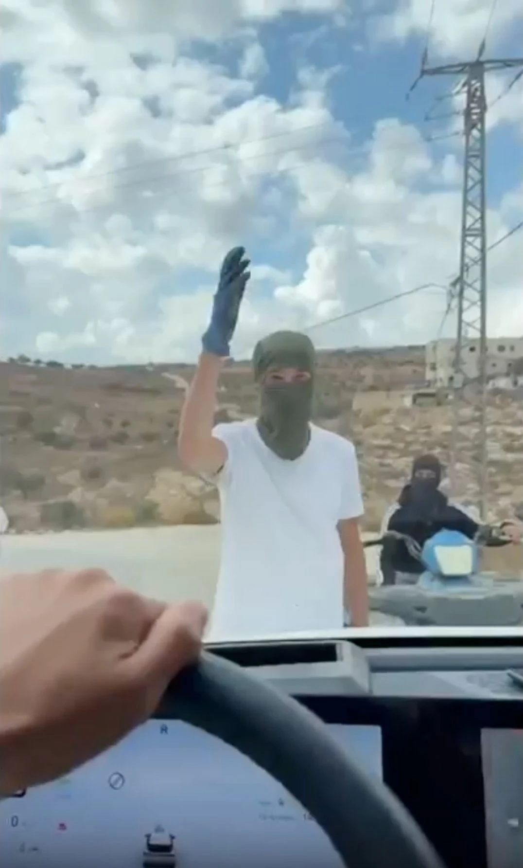In this image made from video provided by Amit Orfali, masked Israeli settlers confront a car driven by Israeli activists in the West Bank village of Taybeh, where European diplomats were attacked on Oct. 17, 2026. (Amit Orfali via AP)