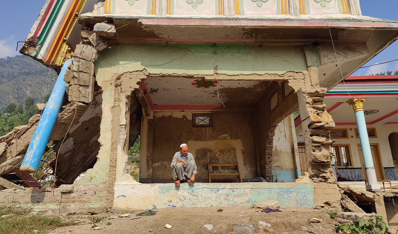 An elderly man sits outside a damaged building, with debris visible around him, in Buner, Khyber Pakhtunkhwa, on September 14, 2026. (AN photo)