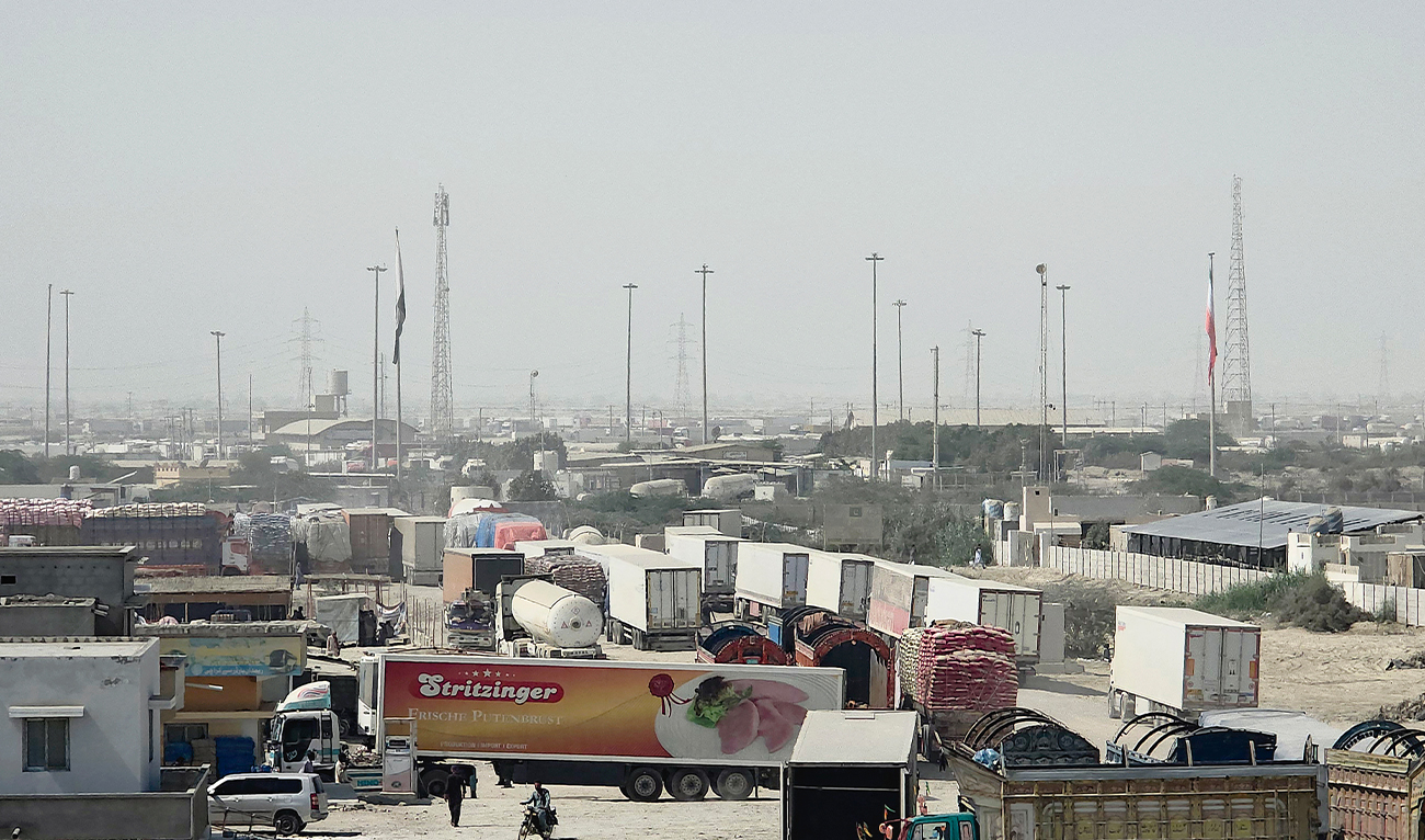 National flags of Pakistan (L) and Iran are pictured near halted cargo trucks at the Gabd-Rimdan zero point border crossing in Pakistan's Balochistan province on October 21, 2026, following the temporary suspension of trade between the two countries.  (AFP)