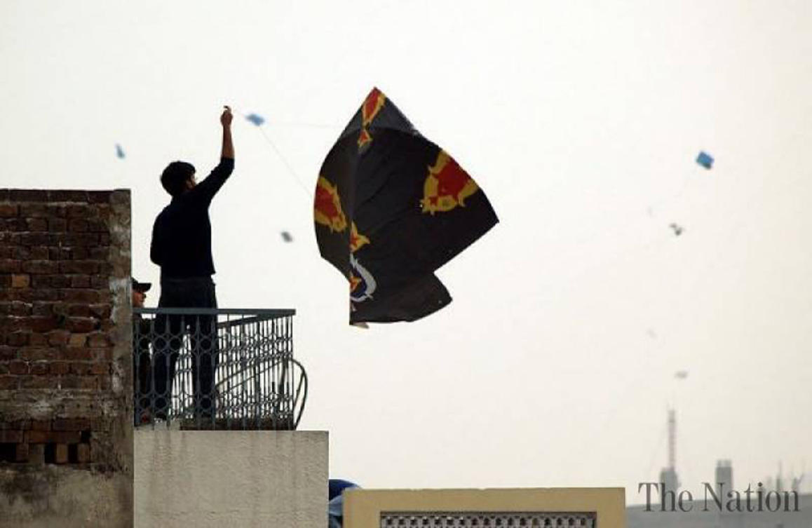 A man raising his kite up in the sky in the Old City, Lahore. (AN photo by Shafiq Malik)