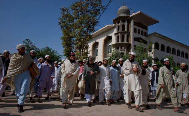 In this file photo, Sami-ul-Haq, center in grey turban, cleric-turned religious-politico leader, Maulana Samiul Haq head of the Islamic seminary Darul Uloom Haqqania, is surrounded by students at his seminary in Akora Khatak, Pakistan. (AP)