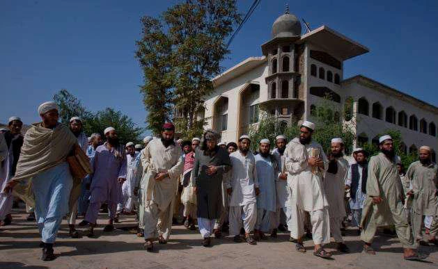 In this file photo, Sami-ul-Haq, center in grey turban, cleric-turned religious-politico leader, Maulana Samiul Haq head of the Islamic seminary Darul Uloom Haqqania, is surrounded by students at his seminary in Akora Khatak, Pakistan. (AP)