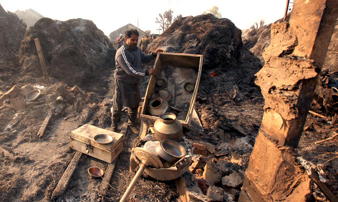 In this file photo, An Indian villager sorts through belongings brought from his house that was damaged in shelling across the India-Pakistan border in Kapoorpur village about 35km from Jammu. (AFP)