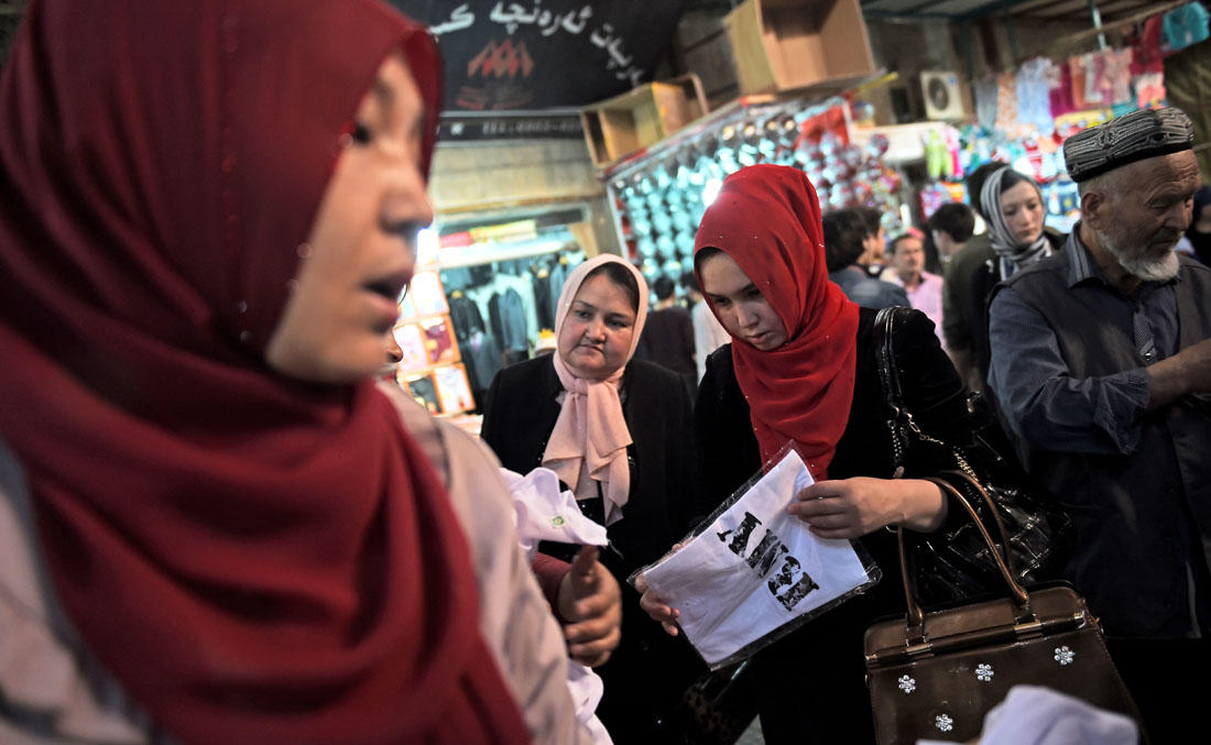 This file photo shows Uighur women looking at clothing in a bazaar in Hotan, in China’s western Xinjiang region on April 15, 2015. (AFP)