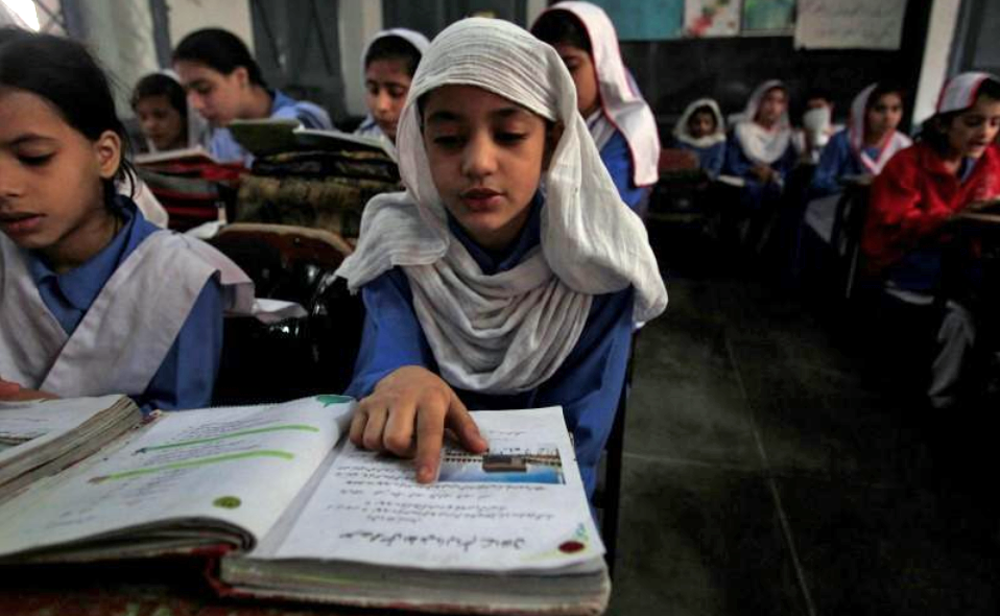 In this file photo, a girl reads a book while attending her daily class with others at a government school in Peshawar Oct. 29, 2014. (REUTERS)