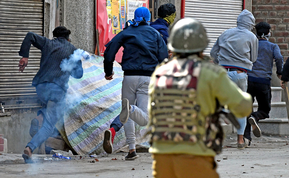 Kashmiri protesters run after Indian police fire tear smoke shells during a second day of strike called by Kashmiri separatists against recent killings in Srinagar on April 3, 2018. (AFP)