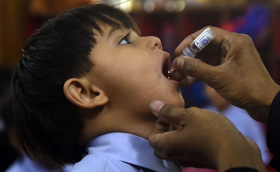 A Pakistani health worker administers polio vaccine drops to a child at a school during a polio vaccination campaign in Karachi on April 9, 2018. (AFP)