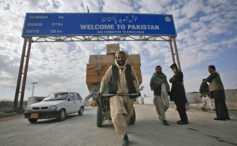 In this file photo, a man passes a road sign while pulling supplies toward the Pak-Afghan border crossing in Chaman Nov. 28, 2011. (REUTERS)