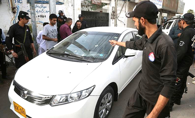 Policemen standing around the car used by Chen Zhu when an assailant opened fire, killing him and injuring his friend in Karachi on Feb. 5. (Photo by Dawn)