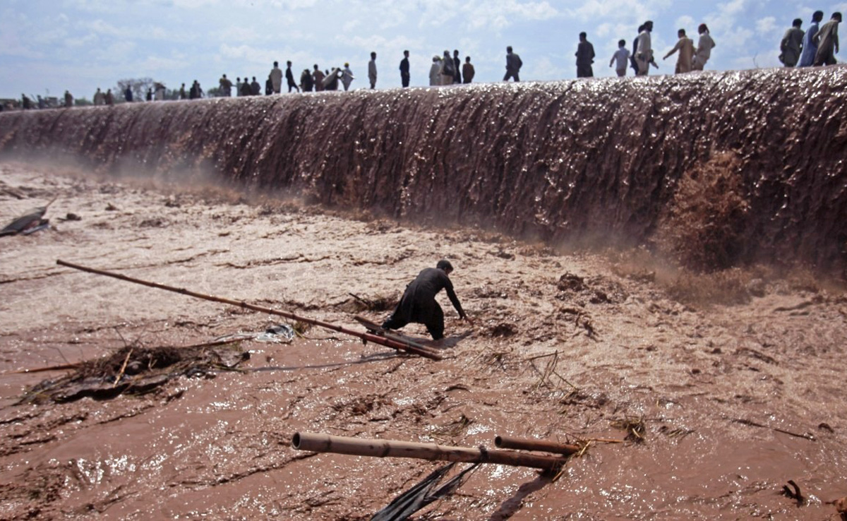 In this file photo, a shopkeeper tries to save belongings as residents use a bridge covered with floodwater after heavy rain in Nowshera District on the outskirts of Peshawar, Pakistan April 4, 2016. (REUTERS)
