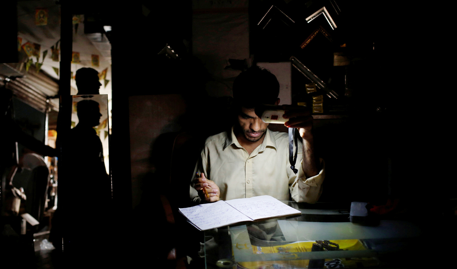 A man uses battery powered light while working at a shop during a power breakdown in Karachi, Pakistan on May 16, 2018. (REUTERS)