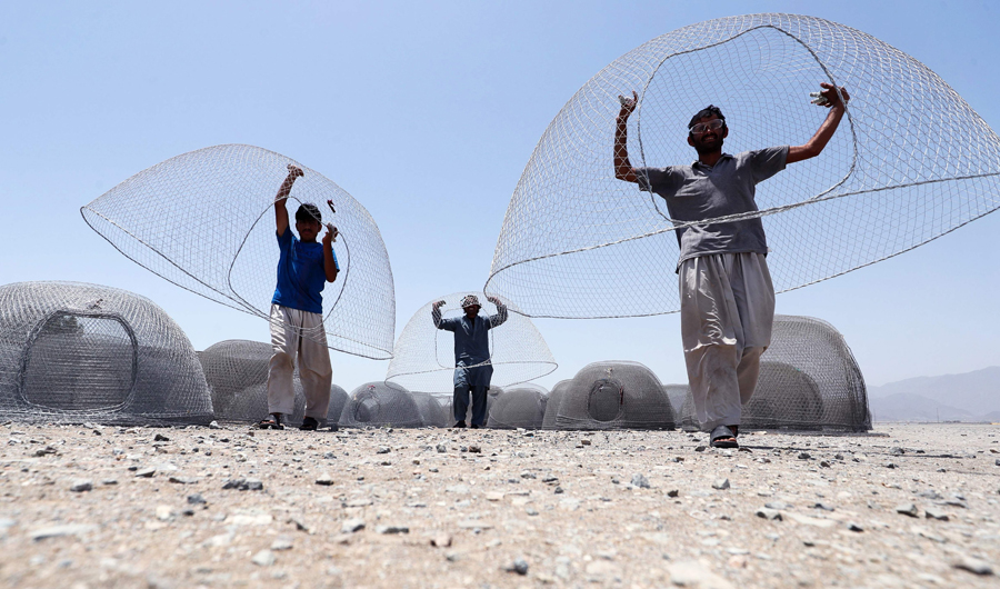 Afghani men carry cages used for fishing in the United Arab Emirates in eastern coastal town of Kalba on May 8, 2018. (AFP)