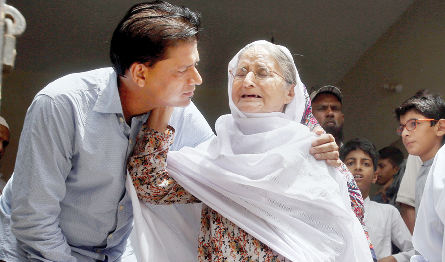 Abdul Aziz Sheikh, left, father of Sabika Sheikh, comforts a woman who arrived to offer condolences at his home in Karachi. (AP)