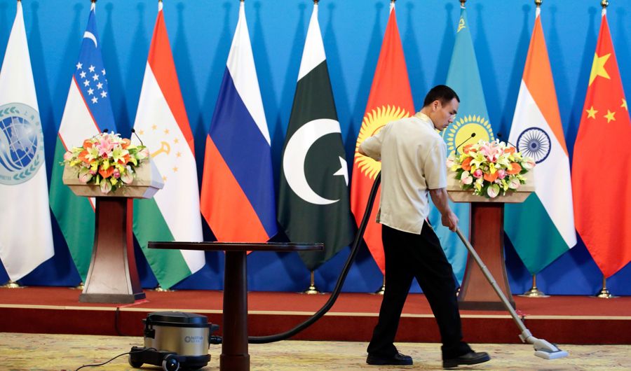 A man cleans the carpet ahead of a news conference by China's Minister of Public Security Zhao Kezhi and Shanghai Cooperation Organisation (SCO) Secretary-General Rashid Alimo in Beijing on May 22, 2018. (AFP)