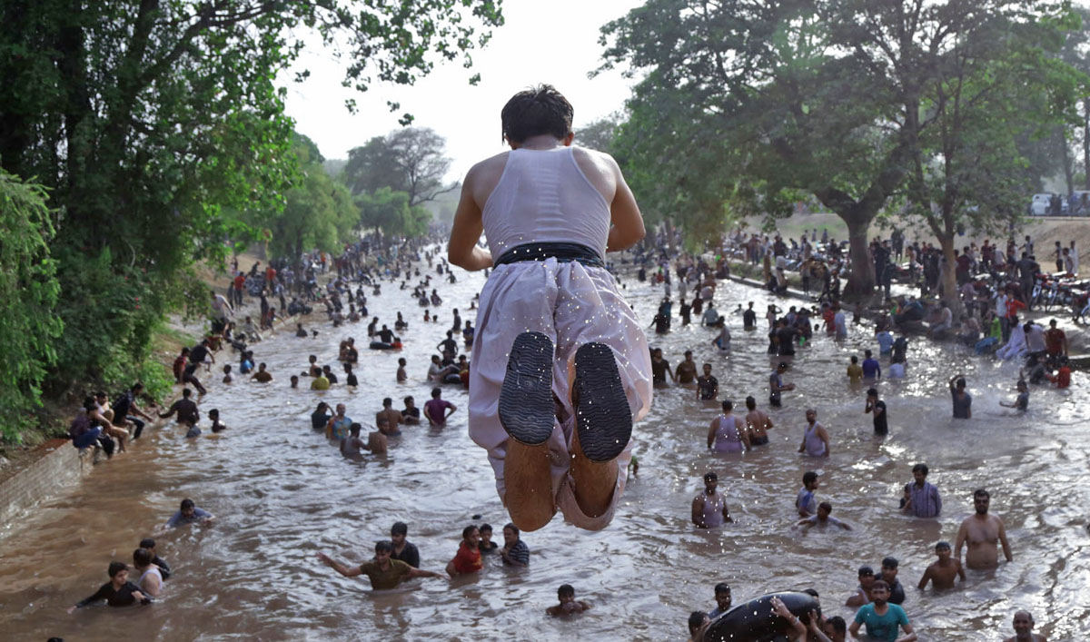 A man jumping in the water from the bridge of the canal. (AN photo by Malik Shafique)
