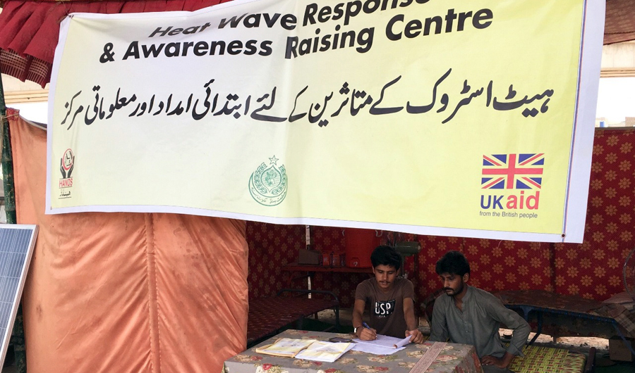 Volunteers at UKaid’s heatwave response and awareness raising center at Malir-15 tell a passerby about preventing heat strokes (Photo by HANDS)