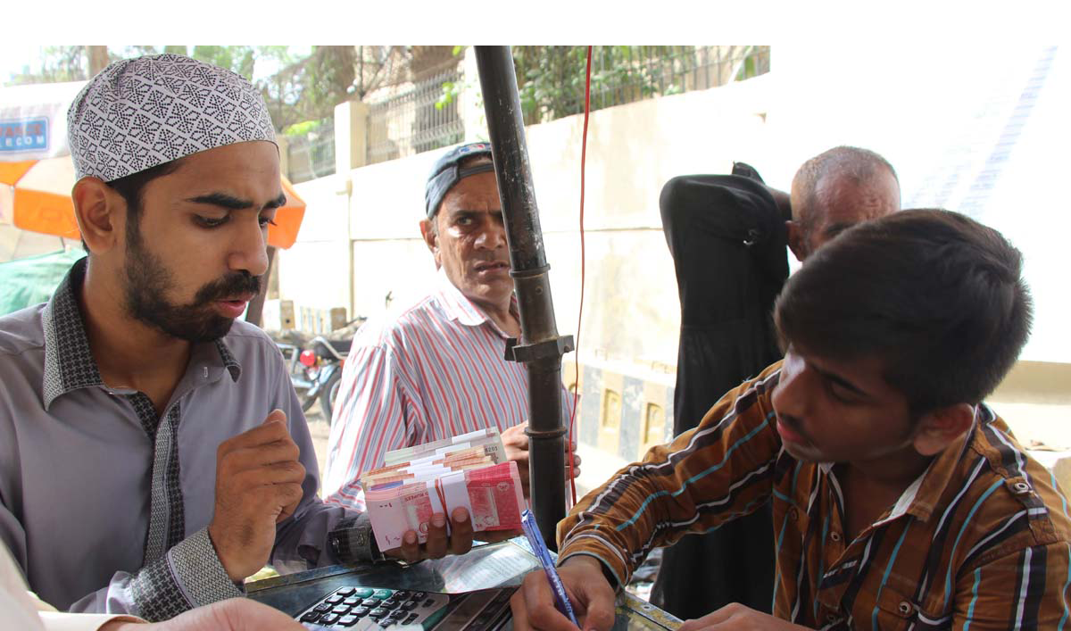 A customer buying new banknotes from a roadside dealer as a passerby looks on (AN photo by Khurshid Ahmed)