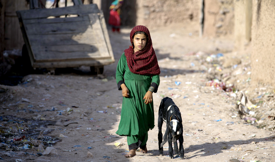 A girl from neighboring Afghanistan, who fled her village with her family due to war and famine, walks in a refugee camp, in a suburb of Islamabad, Pakistan, on June 19, 2018. (AP)